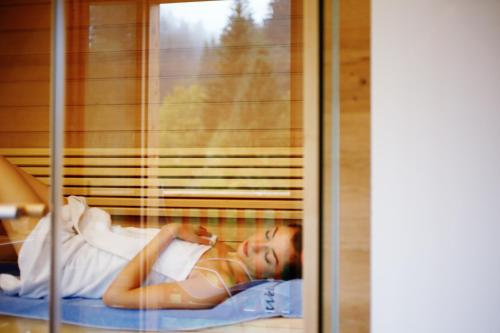 a man laying on a bed looking out a window at Hotel Der Bär in Ellmau