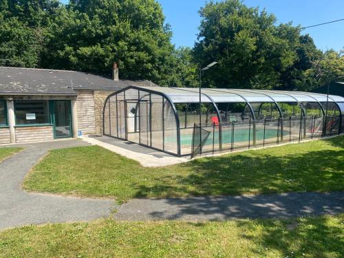a greenhouse in a yard next to a building at GITE Le BELLEVUE 2-4 pers, piscine, billiard et baby-foot in Sainte-Hélène