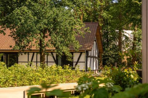 a house with black and white windows and trees at Villa Lodge met Jacuzzi - 8 personen - Woodz Lodges in Heusden - Zolder