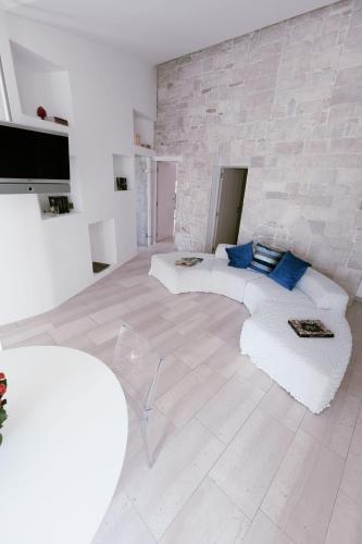 a living room with a white couch and a stone wall at Il Giardino della Giudecca Trani in Trani