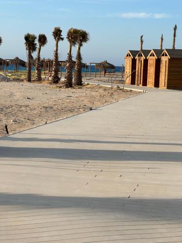 a sidewalk next to a beach with palm trees at North coast Cozy cabin Seaview & Lagon in D-bay I Beach Access Included in Zāwiyat ‘Abd al Mun‘im
