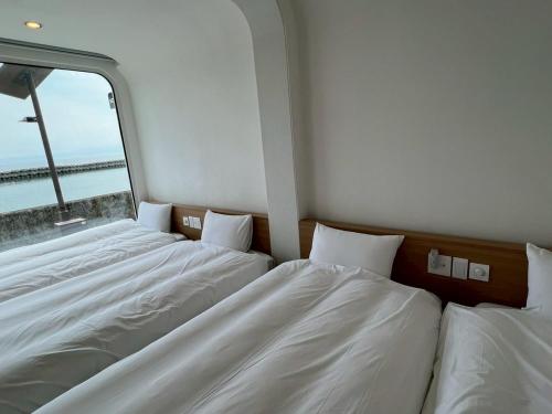 two beds in a room with a window at Thousand Garden Tarumizu in Tarumizu