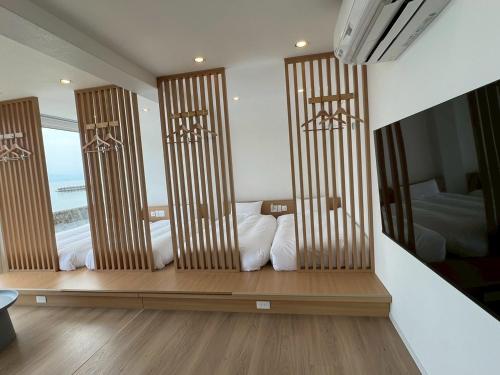 a room with three windows with white pillows on a bench at Thousand Garden Tarumizu in Tarumizu