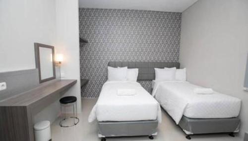 a hotel room with two beds and a mirror at Smart Budget Hotel in Semarang