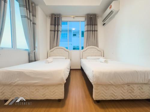 two beds in a room with a window at Serene Heights by Evernent in Miri