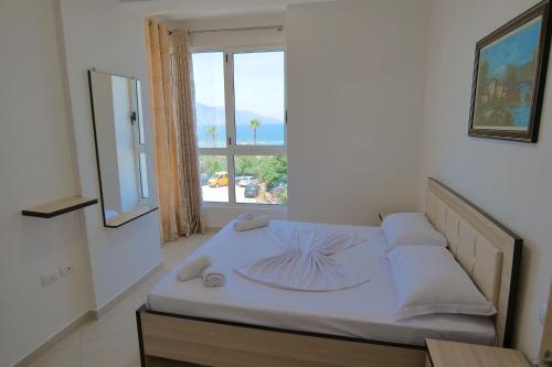 a bedroom with a bed with a large window at Almare Apartments in Vlorë