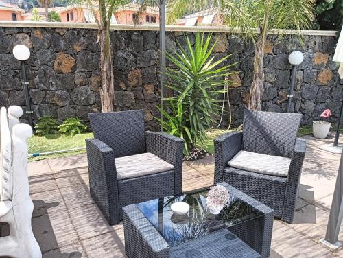 a patio with two chairs and a table and a stone wall at Villa Royal Etna Stars in Zafferana Etnea