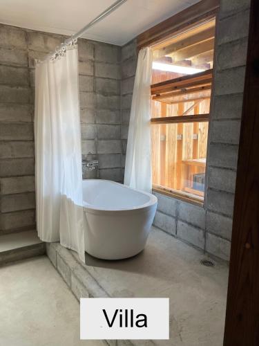 a white bath tub in a bathroom with a window at 水と共に過ごすスモールヴィラ　かふーわ知念　 in Chinen