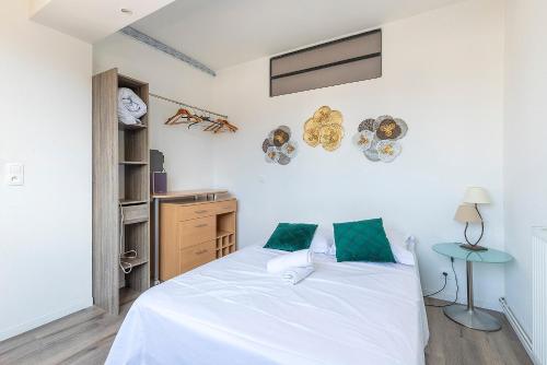 une chambre avec un lit avec des draps blancs et des oreillers verts dans l'établissement Soleil Couchant Balcon Parking Metz Gare Un-Séjour-à-Part, à Metz