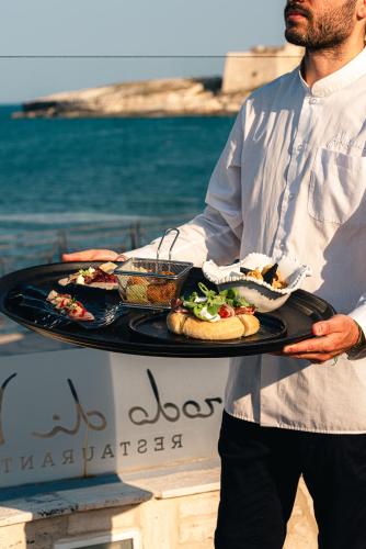 a man holding a tray with food on it at Hotel Approdo di Venere in Vieste