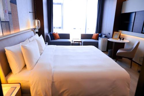 a hotel room with a large white bed and chairs at Wanda Jin Xiaohe Xincheng in Taiyuan