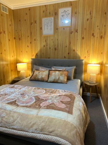 a bedroom with a bed with wooden walls and two lamps at Shore Getaway Spirit of Tasmania- 2 Mins in Norlane