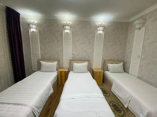 two beds in a room with white sheets at Hotel El Emir in Samarkand