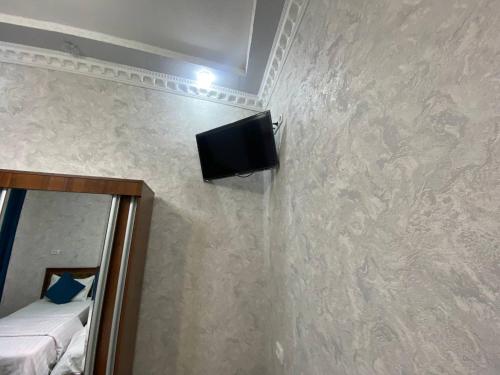 a room with a tv on a wall with a mirror at Hotel El Emir in Samarkand