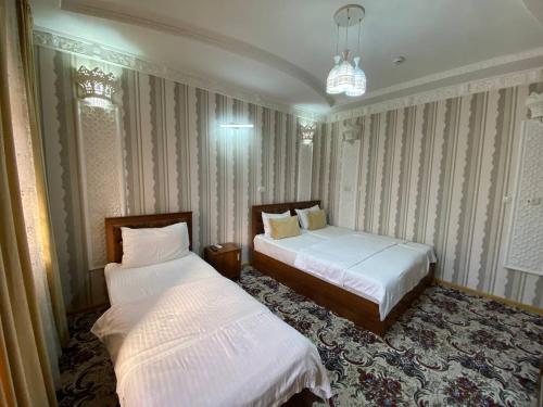 a bedroom with two beds and a chandelier at Hotel El Emir in Samarkand