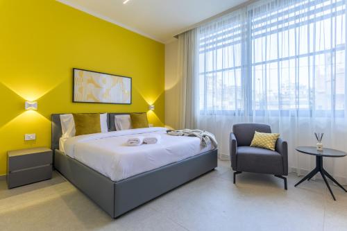 a yellow bedroom with a bed and a chair at CityZen - Boutique Studios in Achrafieh in Beirut