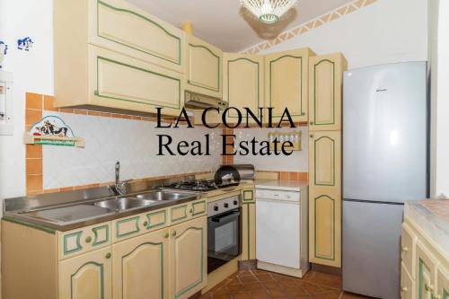 a kitchen with yellow cabinets and a white refrigerator at blue sea villa in Cannigione