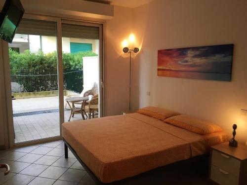 - une chambre avec un lit et une porte coulissante en verre dans l'établissement Casa Vacanze "Marina Vecchia", à Senigallia