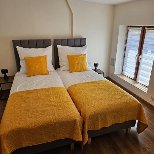 a bedroom with two beds with orange pillows at Apartamenty Tadeusza Kościuszki 3 Bursztynowy in Działdowo