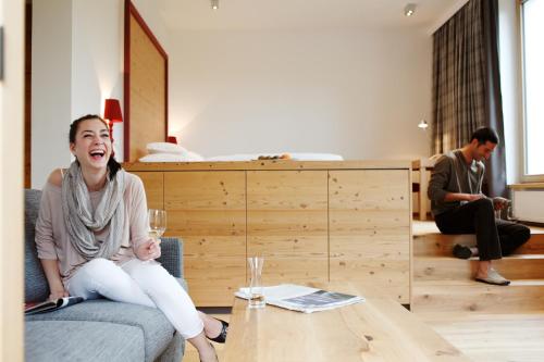 a woman sitting on a couch with a glass of wine at Hotel Der Bär in Ellmau