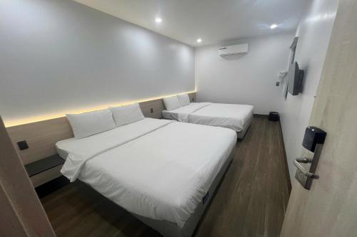 two beds in a small room with white sheets at Thao Trang Luxury Hotel Quang Binh in Dong Hoi