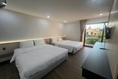 a hotel room with two beds and a window at Thao Trang Luxury Hotel Quang Binh in Dong Hoi