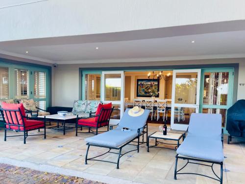 a patio with chairs and tables on a patio at Tremezzo Villa in Plettenberg Bay