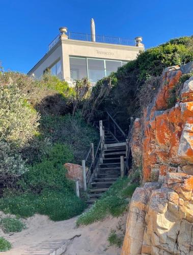 a house on the top of a hill with stairs at Tremezzo Villa in Plettenberg Bay