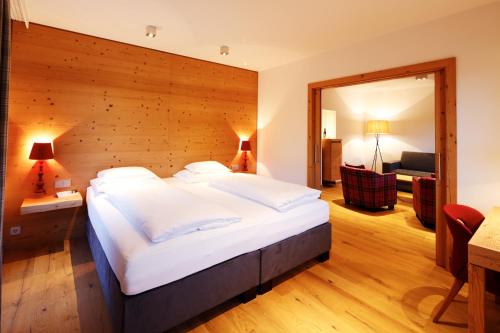 a bedroom with a large bed with a wooden wall at Hotel Der Bär in Ellmau