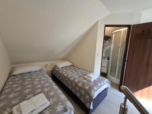 two beds in a small room with a mirror at Beachfront Apartman in Balatonfůzfő