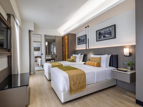 a hotel room with two beds and a television at W Residence Living in Dhaka