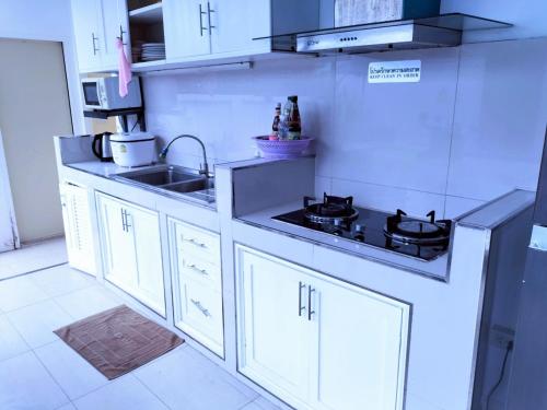 a white kitchen with a sink and a stove at Hunter Hide Pool Villa in Jomtien Beach
