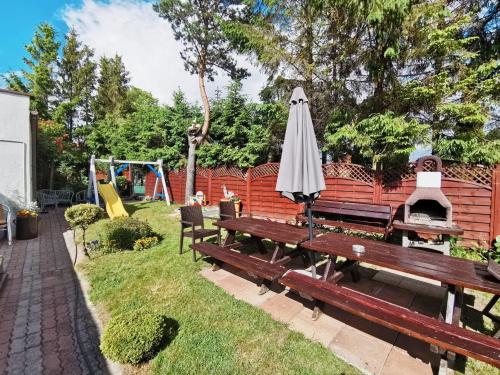 a park with a bench and an umbrella and a playground at Dom Gościnny Wika in Rewal