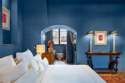 a blue bedroom with a bed and a mirror at The James Suite Hotel Firenze 1564 - Small Luxury Hotels of the World in Florence