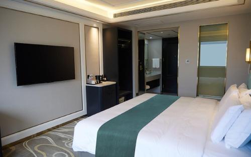 a bedroom with a large bed with a flat screen tv at Taishan Ximei Yinju Hotel, Tai'an in Tai'an