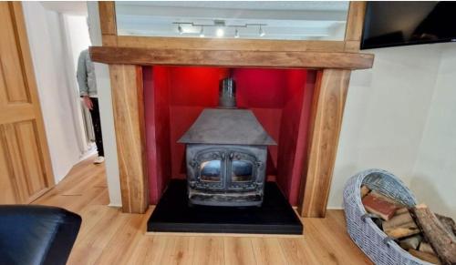 un camino in una stanza con una parete rossa di North Cornwall 2-Bed Detached Period Cottage With Parking a Camelford