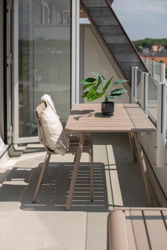 a table and chair on a balcony with a plant at Sous la Mer SOLEIL, luxury apartment in Cadzand centre near beach crossing in Cadzand