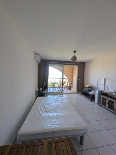 un lit dans une chambre avec une grande fenêtre dans l'établissement Cala Di sognu Moriani plage face à la mer, à San-Nicolao