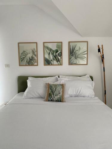 a bedroom with a white bed with four pictures on the wall at Vila Luna in Năvodari