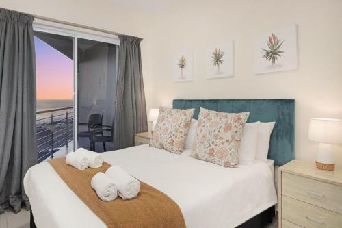 a bedroom with a bed with towels on it at Sunset On Hill 3 in Bloubergstrand