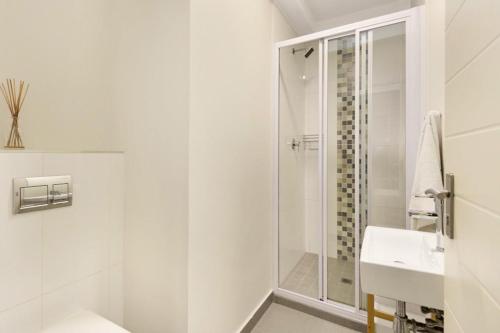 a white bathroom with a shower and a sink at Sunset On Hill 3 in Bloubergstrand