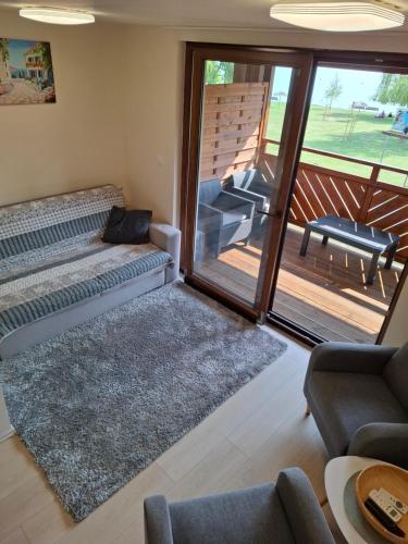 a living room with a couch and a balcony at Beachfront Apartman in Balatonfůzfő