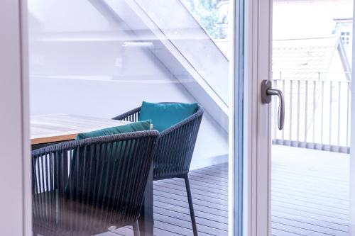 a table and chairs on a balcony with a glass door at Alte Bäckerei Königstein Aparthotel und Café in Königstein an der Elbe