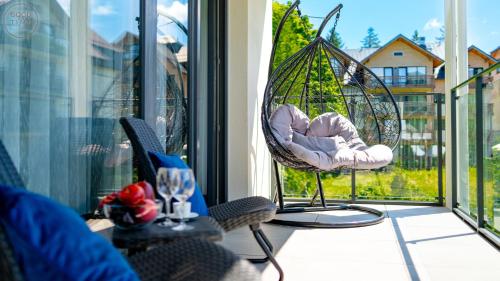 a porch with a swing and a chair on a balcony at Apartamenty Good Time - Belle View - Centrum in Szklarska Poręba