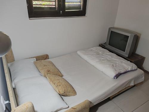 a bed with a tv and pillows in a room at Apartman Čolović in Sutomore