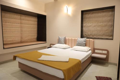SāngliHotel Rajadhiraj的带一张床和两扇窗户的卧室