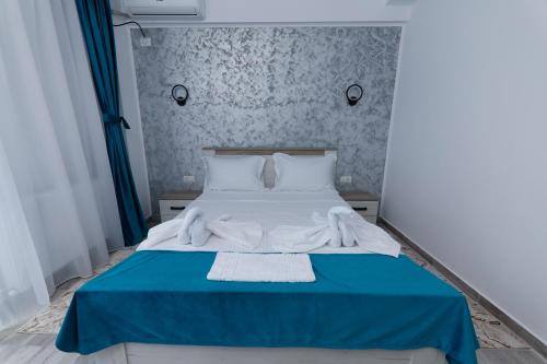 a bedroom with a blue and white bed with towels on it at RUXO Hotel in Mamaia Nord