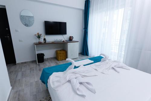 a bedroom with a white bed with a tv on it at RUXO Hotel in Mamaia Nord
