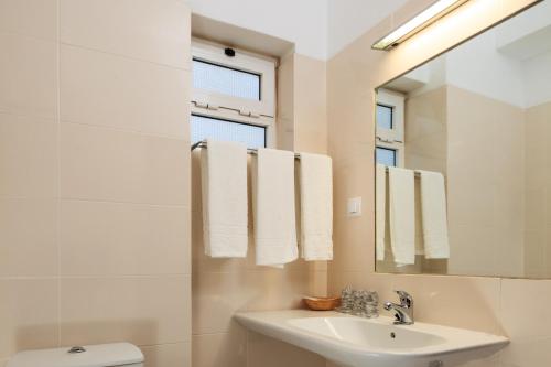 Baño blanco con lavabo y espejo en Guest House Oliveira, en Boliqueime