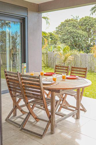 a wooden table and two chairs sitting next to a table at Villa La Confiance - Vue mer-Jardin - By Sister Home in Saint-Benoît